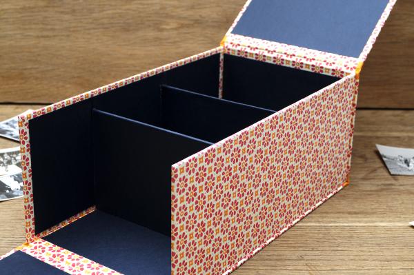 Fotobox offen,innen hauptsächlich schwarz, Bezugspapier partiell zu sehen,drei seperate Fächer,Front flexibel,aufgeklappt,